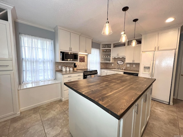 kitchen featuring white refrigerator with ice dispenser, a center island, stainless steel microwave, and butcher block counters