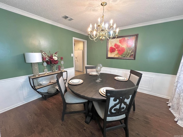 dining room with a textured ceiling, dark hardwood / wood-style floors, an inviting chandelier, and ornamental molding