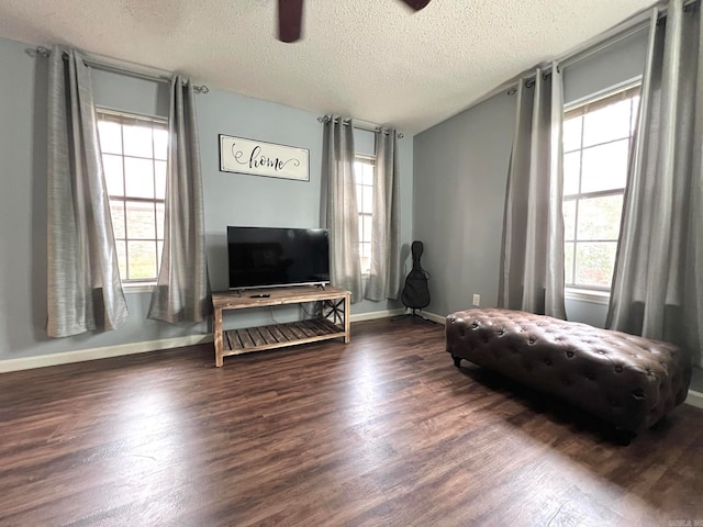 living area featuring a textured ceiling, dark hardwood / wood-style floors, and ceiling fan