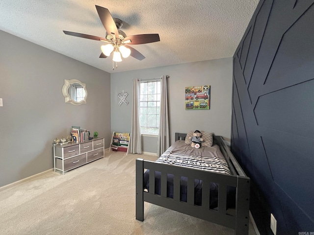 bedroom featuring a textured ceiling, light colored carpet, and ceiling fan