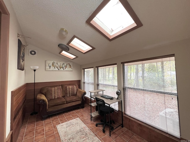 office area with tile patterned flooring, wood walls, lofted ceiling with skylight, and a textured ceiling