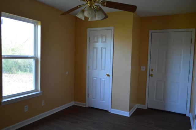 unfurnished bedroom with multiple windows, ceiling fan, and dark hardwood / wood-style floors