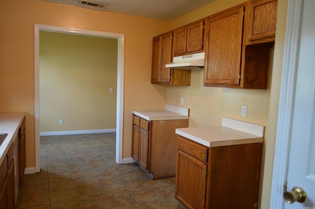 106 W Clinton, Heber Springs, AR 72543 - kitchen with under cabinet range hood, brown cabinets, light countertops, and baseboards