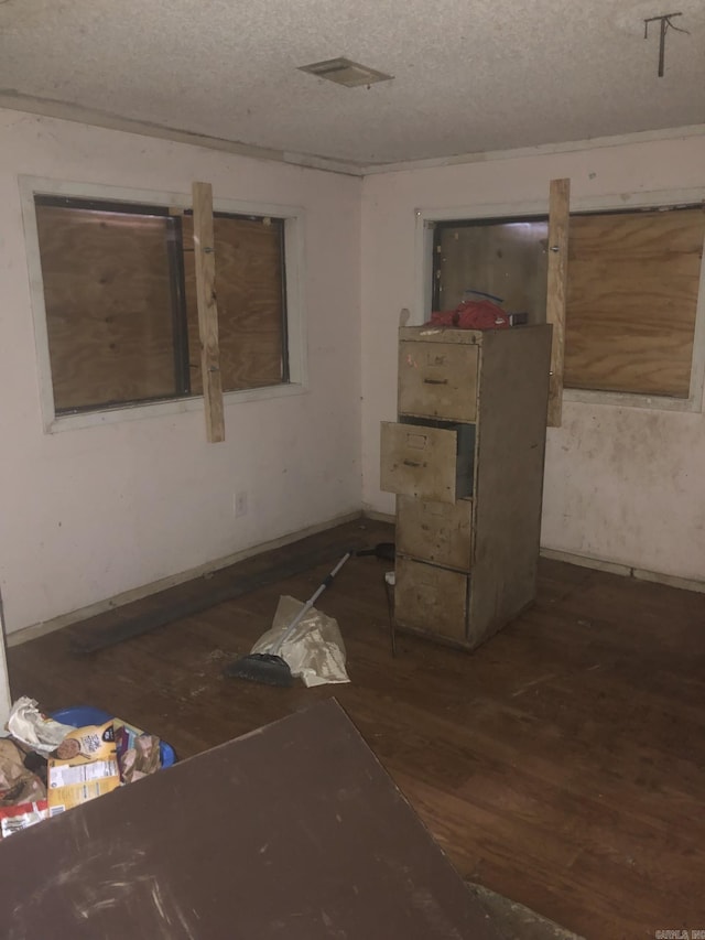 empty room with dark hardwood / wood-style flooring and a textured ceiling