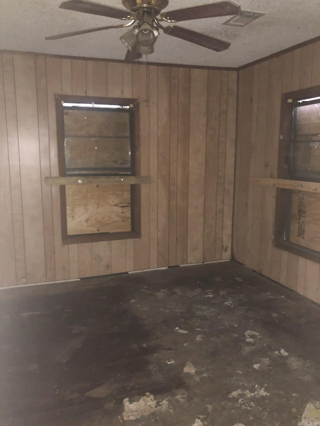 unfurnished room featuring ceiling fan, a textured ceiling, and wooden walls