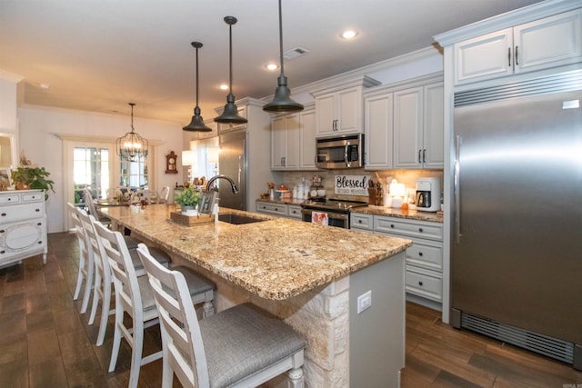 kitchen featuring sink, dark hardwood / wood-style floors, a spacious island, decorative light fixtures, and appliances with stainless steel finishes