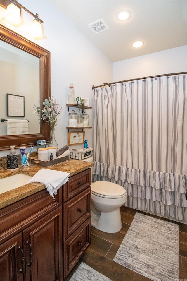 bathroom with wood-type flooring, vanity, toilet, and curtained shower