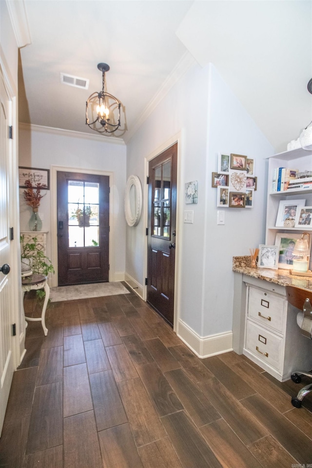 foyer with ornamental molding, dark hardwood / wood-style floors, vaulted ceiling, and a notable chandelier