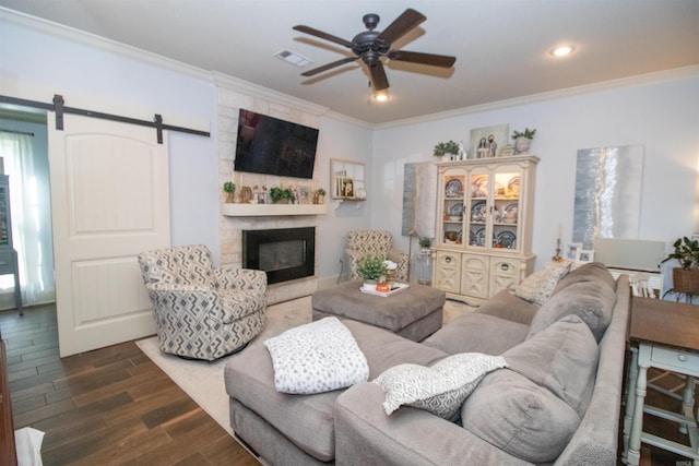 living room featuring a barn door, a large fireplace, dark wood-type flooring, and ornamental molding