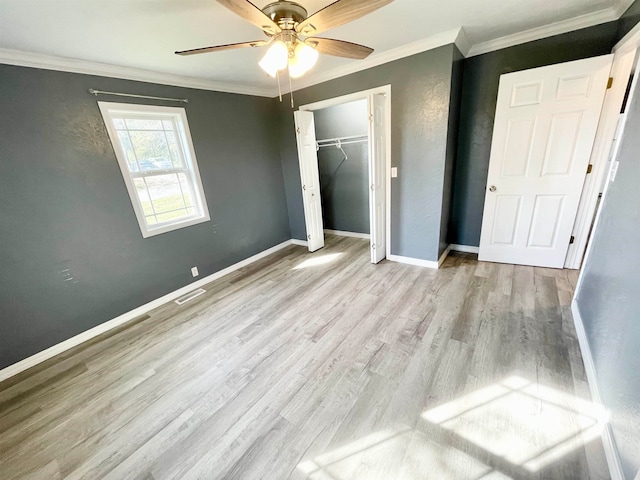 unfurnished bedroom with crown molding, light hardwood / wood-style floors, a closet, and ceiling fan