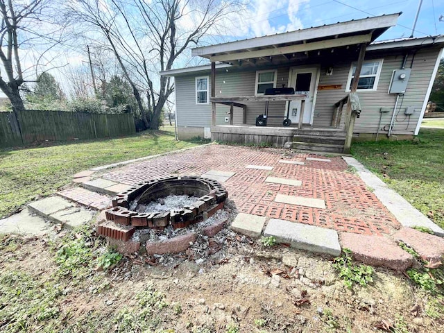 rear view of property featuring a fire pit, a lawn, and a patio