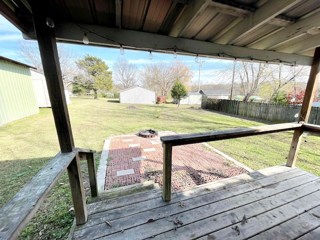 wooden deck with an outdoor fire pit and a lawn