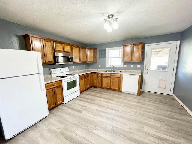 kitchen with sink, white appliances, a textured ceiling, and light wood-type flooring