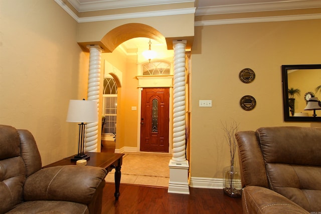 foyer featuring wood-type flooring, decorative columns, and crown molding