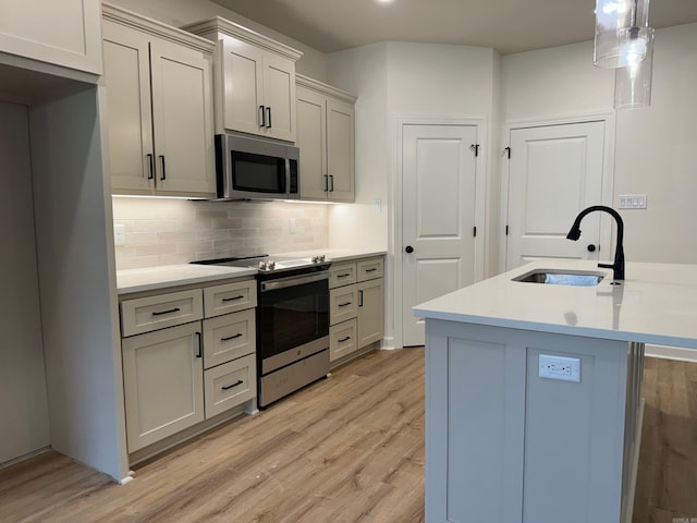 kitchen featuring pendant lighting, backsplash, sink, light hardwood / wood-style flooring, and stainless steel appliances