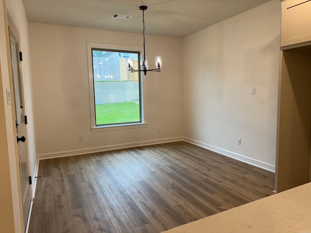 unfurnished dining area with dark hardwood / wood-style flooring and a chandelier