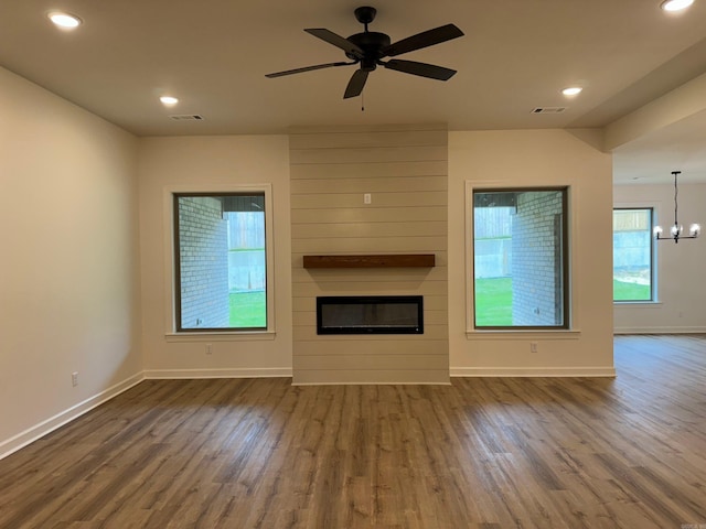 unfurnished living room featuring a fireplace, hardwood / wood-style floors, and ceiling fan with notable chandelier