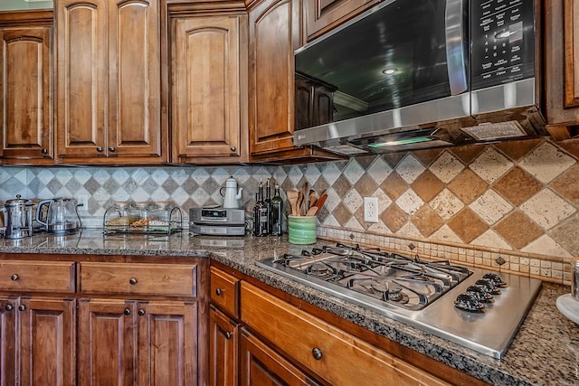 kitchen with dark stone countertops, decorative backsplash, and stainless steel appliances