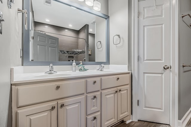 bathroom featuring vanity, a tile shower, and wood-type flooring