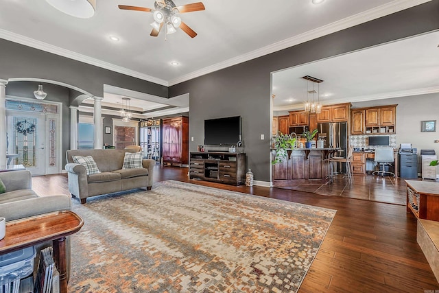 living room featuring dark hardwood / wood-style flooring, ornate columns, ceiling fan, and ornamental molding