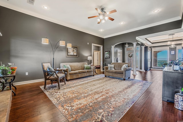 living room featuring ceiling fan, dark hardwood / wood-style flooring, crown molding, and decorative columns