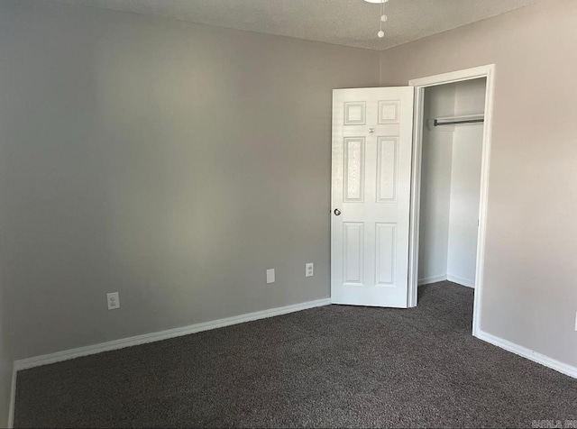 unfurnished bedroom with a textured ceiling and dark colored carpet