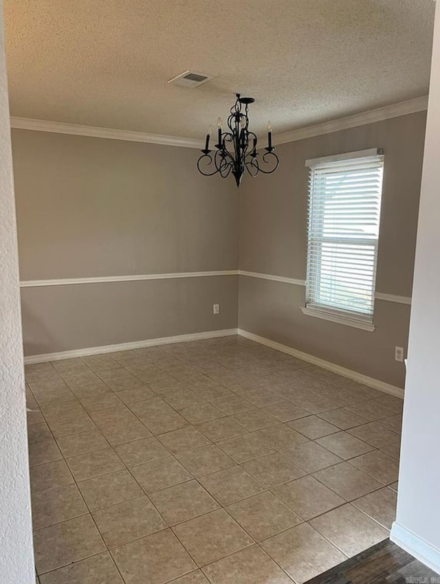 tiled spare room featuring ornamental molding, a textured ceiling, and an inviting chandelier