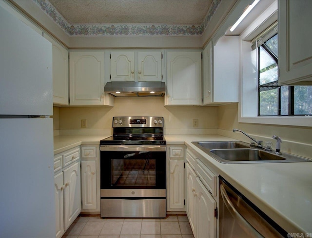 kitchen with appliances with stainless steel finishes, a textured ceiling, white cabinetry, and sink