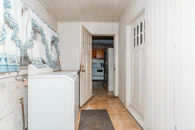 clothes washing area featuring washer / dryer, light tile patterned floors, and wooden walls