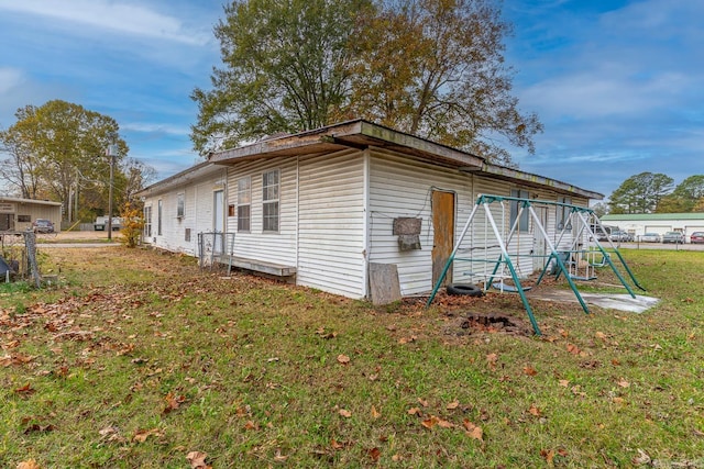 view of side of home with a playground and a lawn