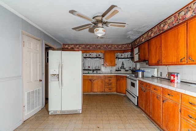 kitchen featuring tasteful backsplash, ornamental molding, white appliances, ceiling fan, and tile counters