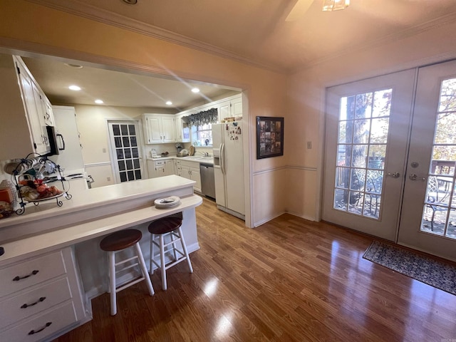 kitchen with light wood-type flooring, a breakfast bar area, white cabinets, and appliances with stainless steel finishes