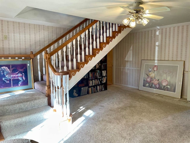 stairway with ceiling fan, ornamental molding, and carpet