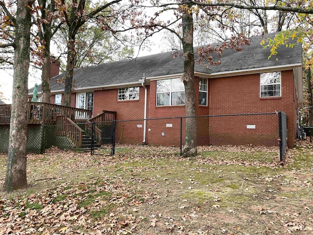 back of property featuring a deck and a lawn