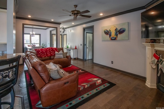 living room featuring ceiling fan with notable chandelier, ornamental molding, and dark wood-type flooring