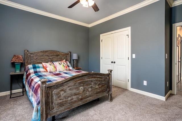 carpeted bedroom featuring ornamental molding, a closet, baseboards, and a ceiling fan