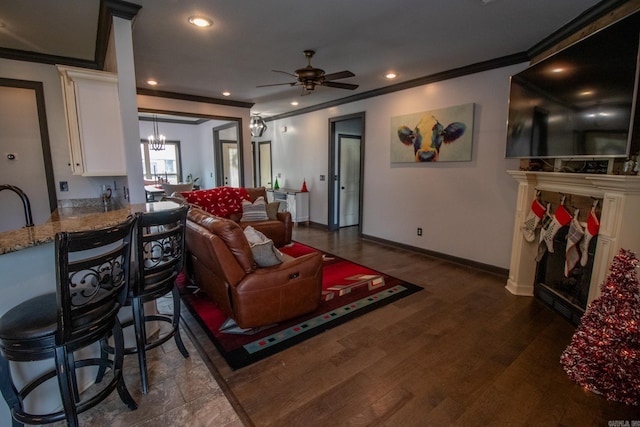 living room with recessed lighting, ceiling fan with notable chandelier, dark wood-style flooring, baseboards, and crown molding