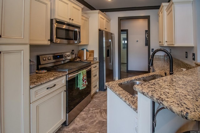 kitchen with stainless steel appliances, a sink, a peninsula, and light stone countertops