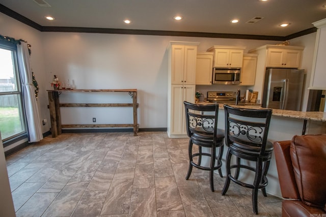 kitchen featuring light stone counters, visible vents, a kitchen breakfast bar, ornamental molding, and appliances with stainless steel finishes