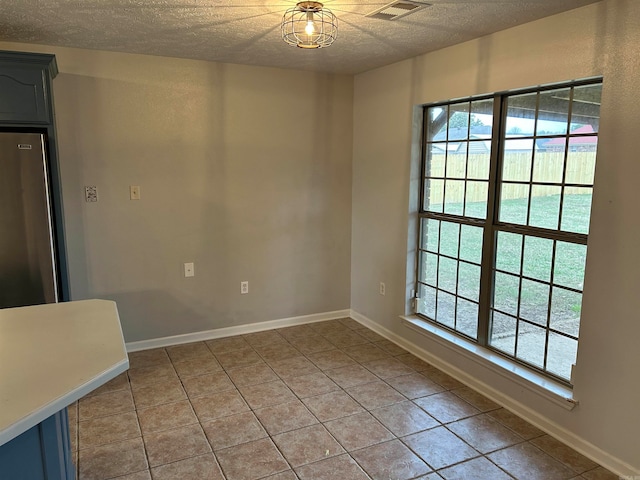 tiled empty room with plenty of natural light and a textured ceiling