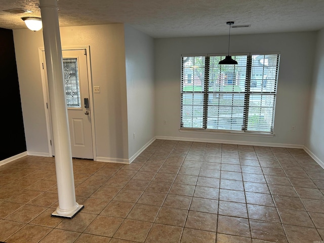 interior space with tile patterned flooring, ornate columns, and a textured ceiling