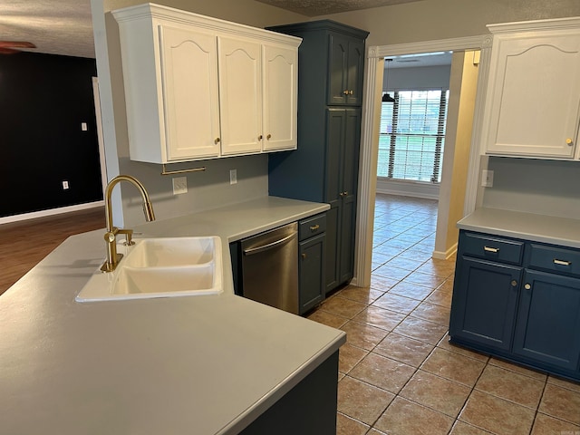 kitchen with stainless steel dishwasher, white cabinets, light tile patterned floors, and sink