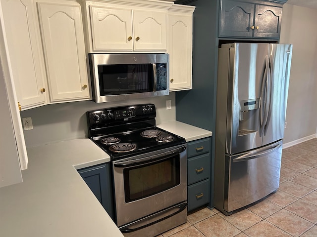 kitchen featuring light tile patterned floors, stainless steel appliances, and white cabinetry