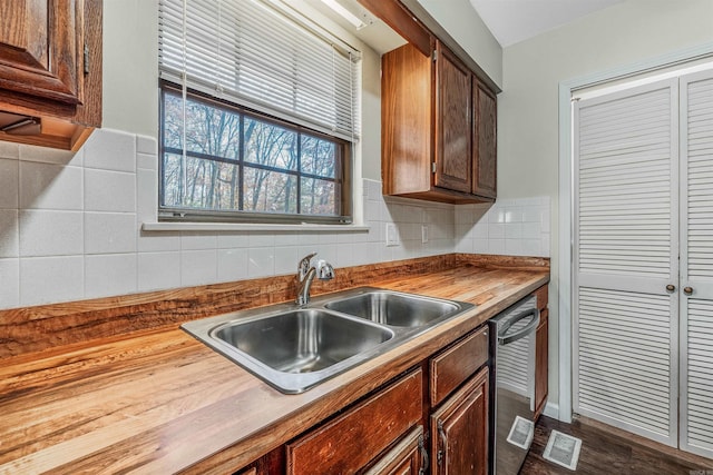 kitchen with wood counters, sink, stainless steel dishwasher, dark hardwood / wood-style floors, and decorative backsplash