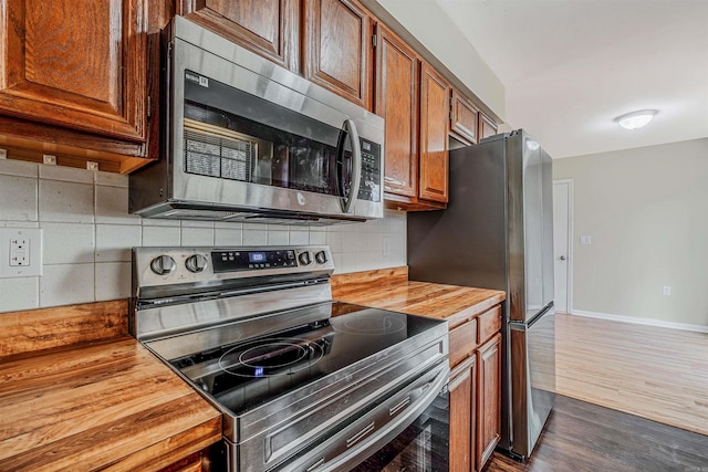 kitchen featuring wood counters, stainless steel appliances, tasteful backsplash, and dark wood-type flooring