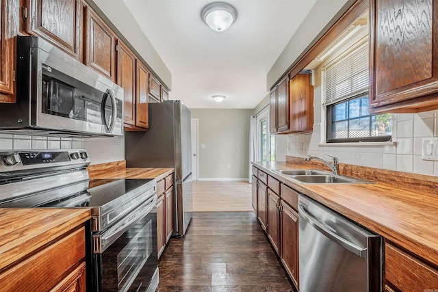 kitchen with wood counters, appliances with stainless steel finishes, backsplash, and dark hardwood / wood-style floors