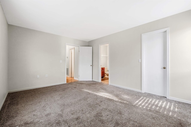 unfurnished bedroom featuring ensuite bath, light carpet, and a closet