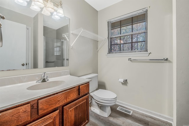 bathroom featuring vanity, toilet, wood-type flooring, and a shower with door