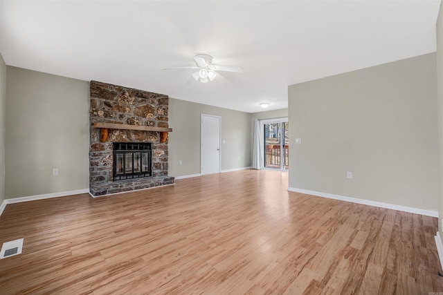 unfurnished living room with ceiling fan, a stone fireplace, and light hardwood / wood-style flooring