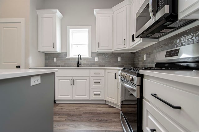 kitchen with wood-type flooring, stainless steel appliances, white cabinetry, and sink